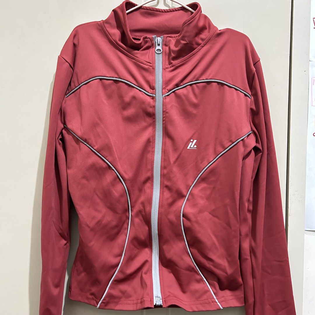 Red Athletic Zip-Up Jacket with Thumbholes (Category: Activewear) located in Manila. Submitted by frances_001 (Listing ID 1465691920, Image 2). Description: - Color: Red with grey piping and white logo - Size: Medium (M) - Fit: Fitted waist with curved seam details - Features: Stand-up collar, full front zip, and long sleeves with thumbhole cuffs - Material: Smooth, stretchy athletic fabric.