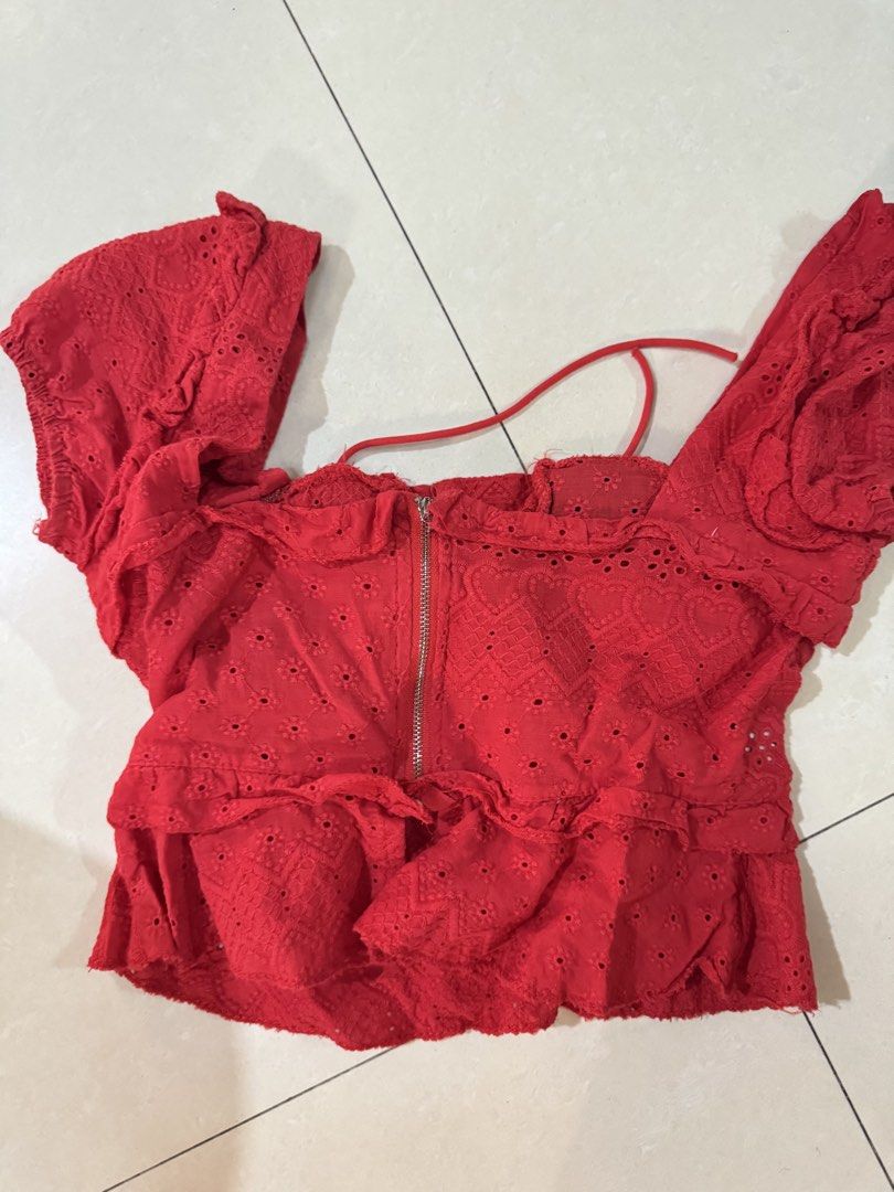 Red eyelet lace corset crop top with ruffles whimsy (Category: Blouses) located in Quezon City. Submitted by sweetlyluxe (Listing ID 1465601384, Image 3). Description: - Color: Bright red with subtle heart patterns - Material: Lightweight eyelet embroidery fabric - Design: Front lace-up detail, corset-style bust cups, short ruffle sleeves, and flared hem - Closure: Exposed silver zipper at the back - Style: Summery and trendy crop top for birthda
