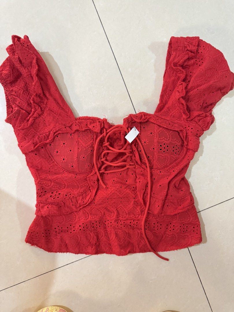 Red eyelet lace corset crop top with ruffles whimsy (Category: Blouses) located in Quezon City. Submitted by sweetlyluxe (Listing ID 1465601384, Image 1). Description: - Color: Bright red with subtle heart patterns - Material: Lightweight eyelet embroidery fabric - Design: Front lace-up detail, corset-style bust cups, short ruffle sleeves, and flared hem - Closure: Exposed silver zipper at the back - Style: Summery and trendy crop top for birthda
