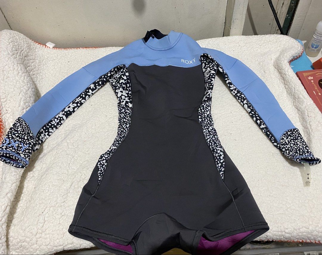 Roxy Women's Springsuit Wetsuit (Category: Rash guard) located in Manila. Submitted by resi.diaz (Listing ID 1465751371, Image 1). Description: - Brand: Roxy - Size: 4 - Design: Light blue, dark grey, and black floral pattern with purple inner lining - Features: Long sleeves, short bottoms, back zip entry, and hook-and-loop collar closure.
