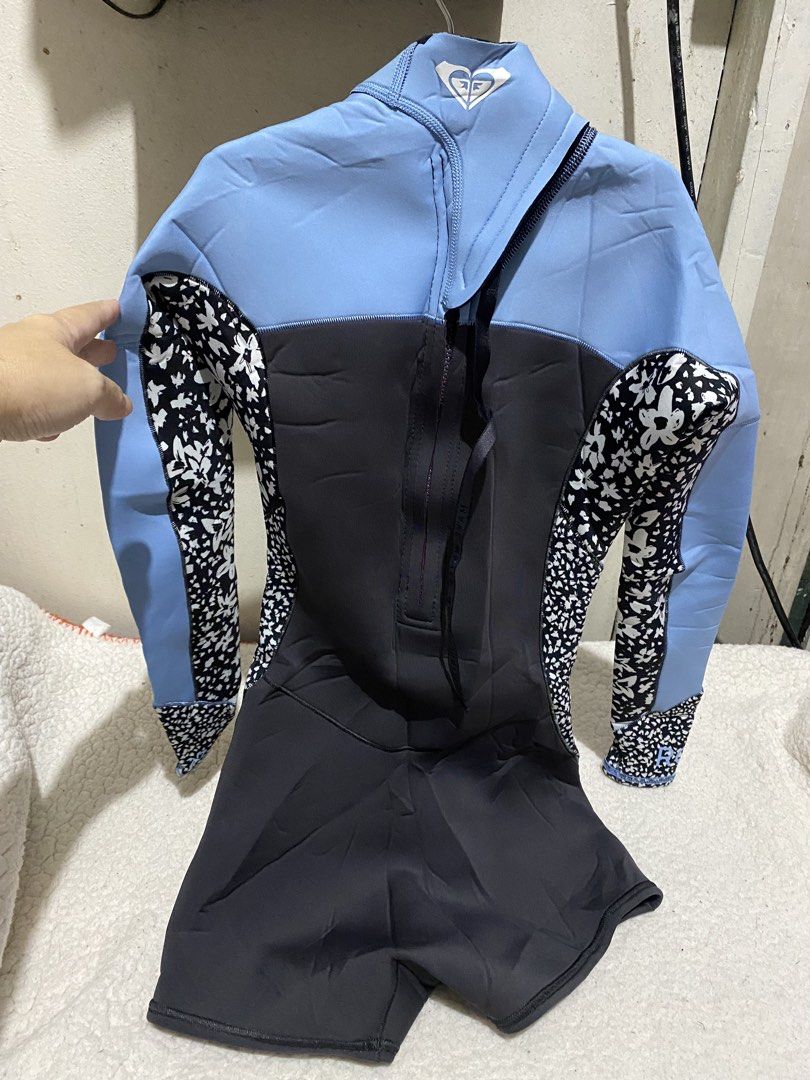 Roxy Women's Springsuit Wetsuit (Category: Rash guard) located in Manila. Submitted by resi.diaz (Listing ID 1465751371, Image 3). Description: - Brand: Roxy - Size: 4 - Design: Light blue, dark grey, and black floral pattern with purple inner lining - Features: Long sleeves, short bottoms, back zip entry, and hook-and-loop collar closure.