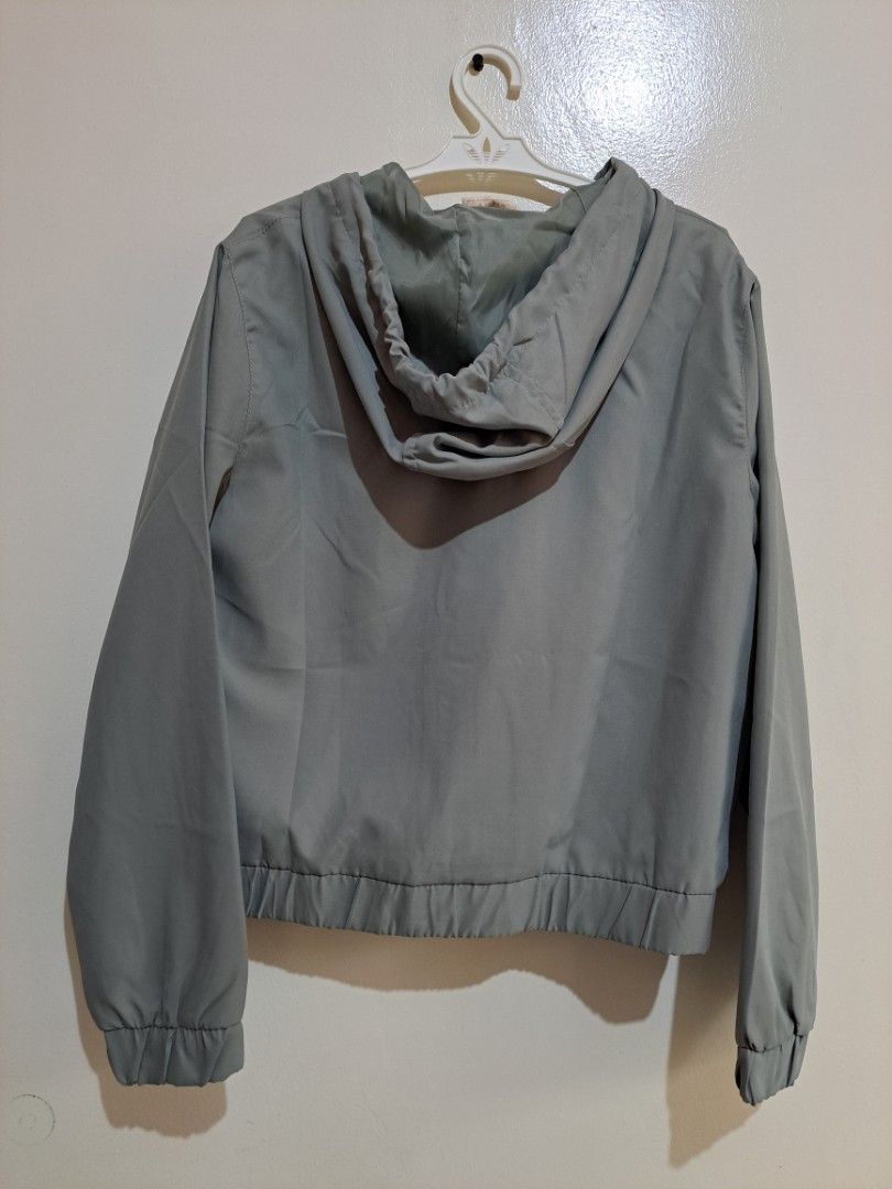Sage Green Windbreaker Jacket (Category: Coats, Jackets and Outerwear) located in Manila. Submitted by yselles__ (Listing ID 1465606395, Image 3). Description: - Closure: Full front zipper - Features: Attached hood and two large chest utility pockets - Comfort: Elastic cuffs and hemline for a snug fit - Lining: Matching tone inside lining - Condition: Clean, solid construction, perfect for everyday casual wear.