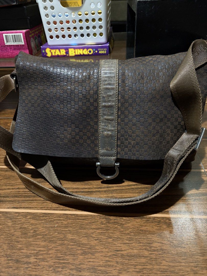 Salvatore Ferragamo Brown Checkered Messenger Bag (Category: Luxury Bags & Wallets) located in Bulacan. Submitted by love2loved (Listing ID 1465672062, Image 1). Description: Brown checkered messenger bag by Salvatore Ferragamo. Textured leather body with a sturdy canvas strap featuring the brand name. Magnetic front closure with a metal ring detail. Extra zippered compartment on the back flap. Roomy interior, great everyday carryall for daily co
