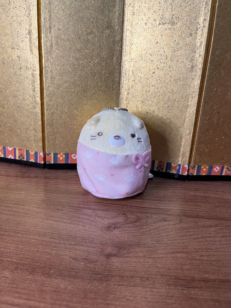 San-X Sumikko Gurashi Neko Plush Keychain (Category: Plushies & Soft Toys) located in Gapan. Submitted by lunashop14 (Listing ID 1465587137, Image 1). Description: - Authentic San-X Sumikkogurashi Neko plush - Wearing an adorable pink sleeping bag with white paw prints and polka dots, plus a small pink ribbon - Includes a ball chain for easy hanging on bags or keys - Official 2023 tag attached - Pristine, clean condition with no stains or damage.