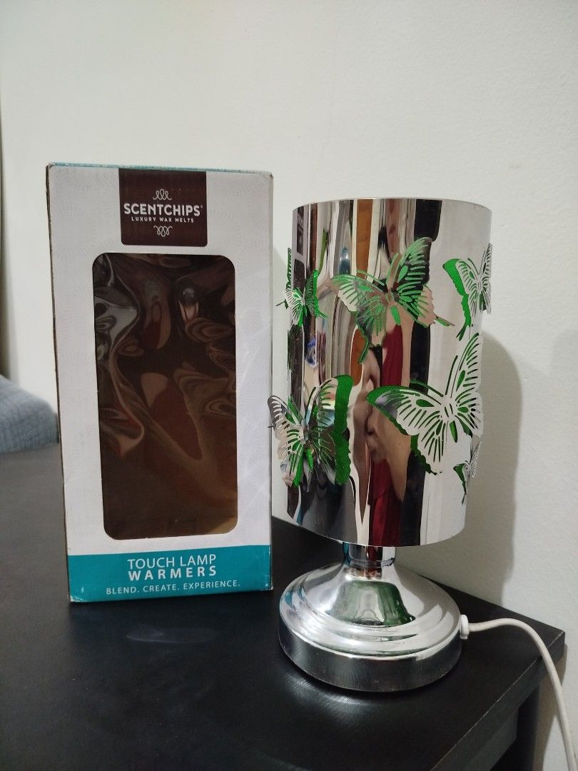 Scentchips Butterfly Touch Lamp Warmer (Category: Lighting) located in Quezon City. Submitted by luckycitrine (Listing ID 1465668636, Image 1). Description: - Brand: Scentchips - Design: Shiny silver finish with cutout butterflies - Function: Touch-activated base to turn on and adjust warmth - Use: Works with wax melts for effortless home fragrance - Includes: Original retail box and attached white cord - Perfect for: Bedroom or living area table