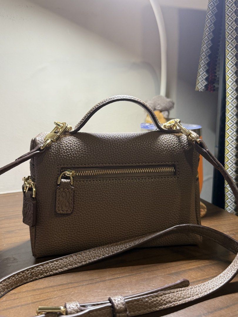 Shoulder bag (Category: Cross-body Bags) located in Makati City. Submitted by joyfulliving22 (Listing ID 1465597010, Image 2). Description: - Material: Premium taupe pebbled PU leather - Hardware: Elegant gold-tone zippers and signature small gold bow logo - Straps: Includes a sturdy top handle and a matching adjustable shoulder strap - Compartments: Main zip compartment plus a convenient exterior back pocket - Interior: Clean, matching leather l