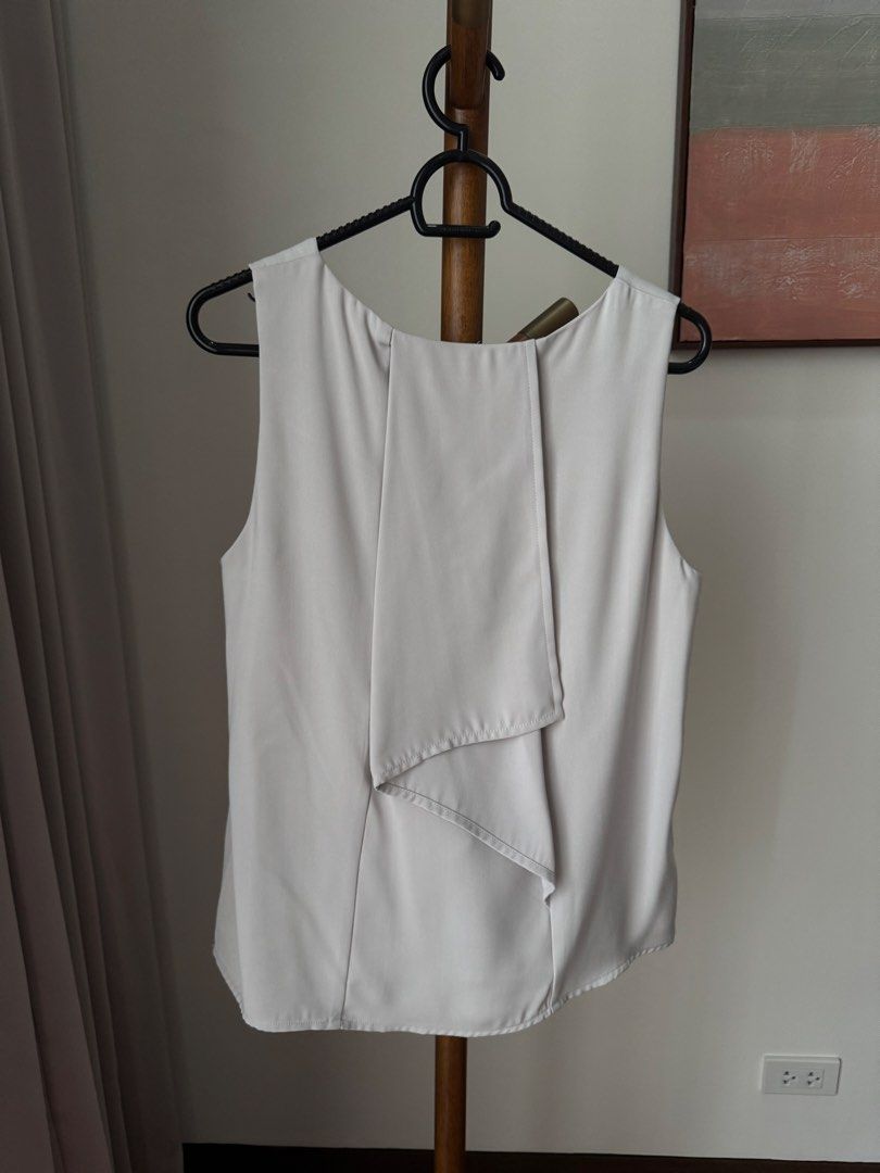 Sleeveless Top Off-White (Category: Sleeveless) located in Pasig City. Submitted by kutleyn (Listing ID 1465672492, Image 3). Description: - Brand: Ellysage - Color: Off-white - Style: Sleeveless top with scoop neckline and unique back drape flap detail - Size: UK 12, US 8, EUR 40 - Material: Lightweight and comfortable fabric - Versatility: Easy to style with jeans or skirts for work or casual days - Condition: Excellent, clean, with no stains o
