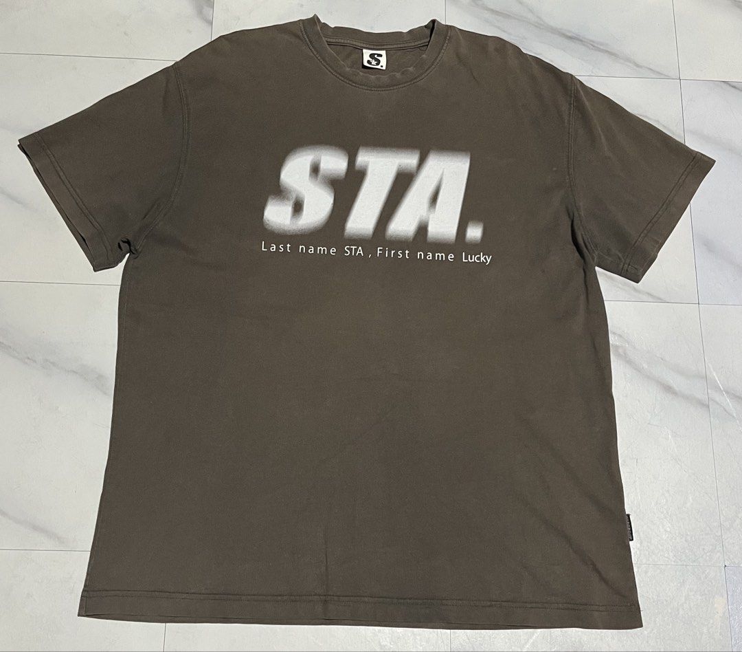 STA. Brown Graphic Tee (Category: Tshirts & Polo Shirts ) located in Cavite. Submitted by christianzuuu (Listing ID 1465725738, Image 1). Description: - Color: Brown with large white 'STA. Last name STA, First name Lucky' front graphic - Design: Large stylized 'S' logo with a star element on the back - Size: 29 inches length x 22.5 inches across the chest (relaxed fit) - Material: Comfortable cotton blend - Condition: Minor fading consistent with