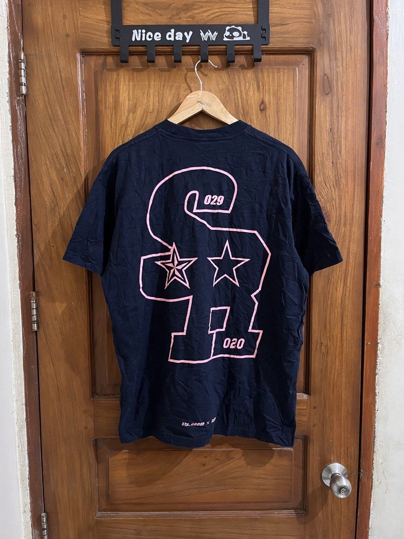 STA_GROUP x Remedy Dark Blue Graphic Tee (Category: Tshirts & Polo Shirts ) located in Bula. Submitted by thrift.wyn (Listing ID 1465599491, Image 2). Description: - Brand: STA_GROUP x Remedy - Color: Dark blue - Design: Small collegiate chest print with a large pink graphic print and star details on the back - Details: Branded woven tag on collar - Fit: Relaxed fit - Material: Comfortable cotton - Condition: Great casual everyday piece.