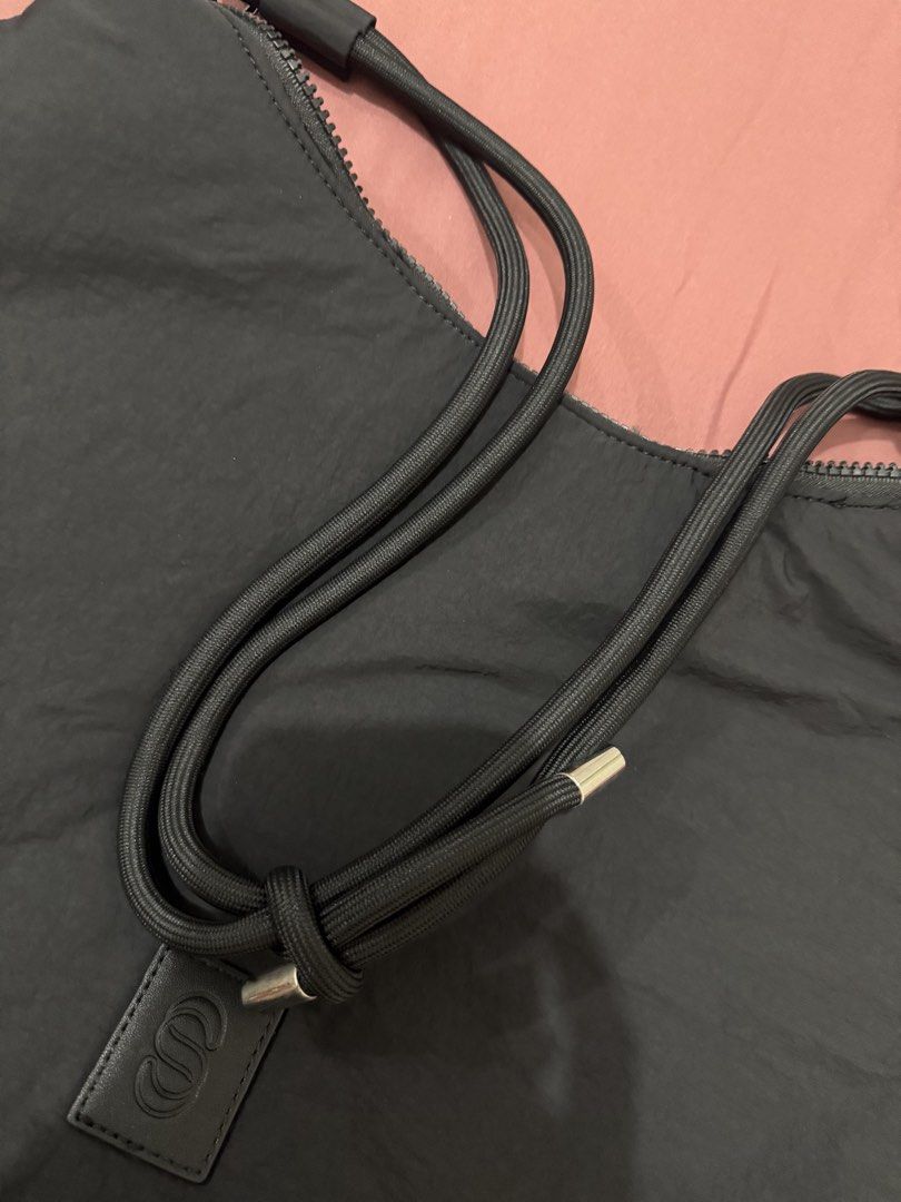 Straighforward Black Nylon Shoulder Bag With Rope Strap (Category: Shoulder Bags) located in Manila. Submitted by aaaine (Listing ID 1465755552, Image 2). Description: - Color & Material: Black nylon, lightweight and easy to carry daily - Straps & Hardware: Thick rope straps with metal aglets and O-ring details - Closure & Interior: Secure top zip closure, dark fabric lining, and one small slip pocket - Branding: Structured leatherette patch with