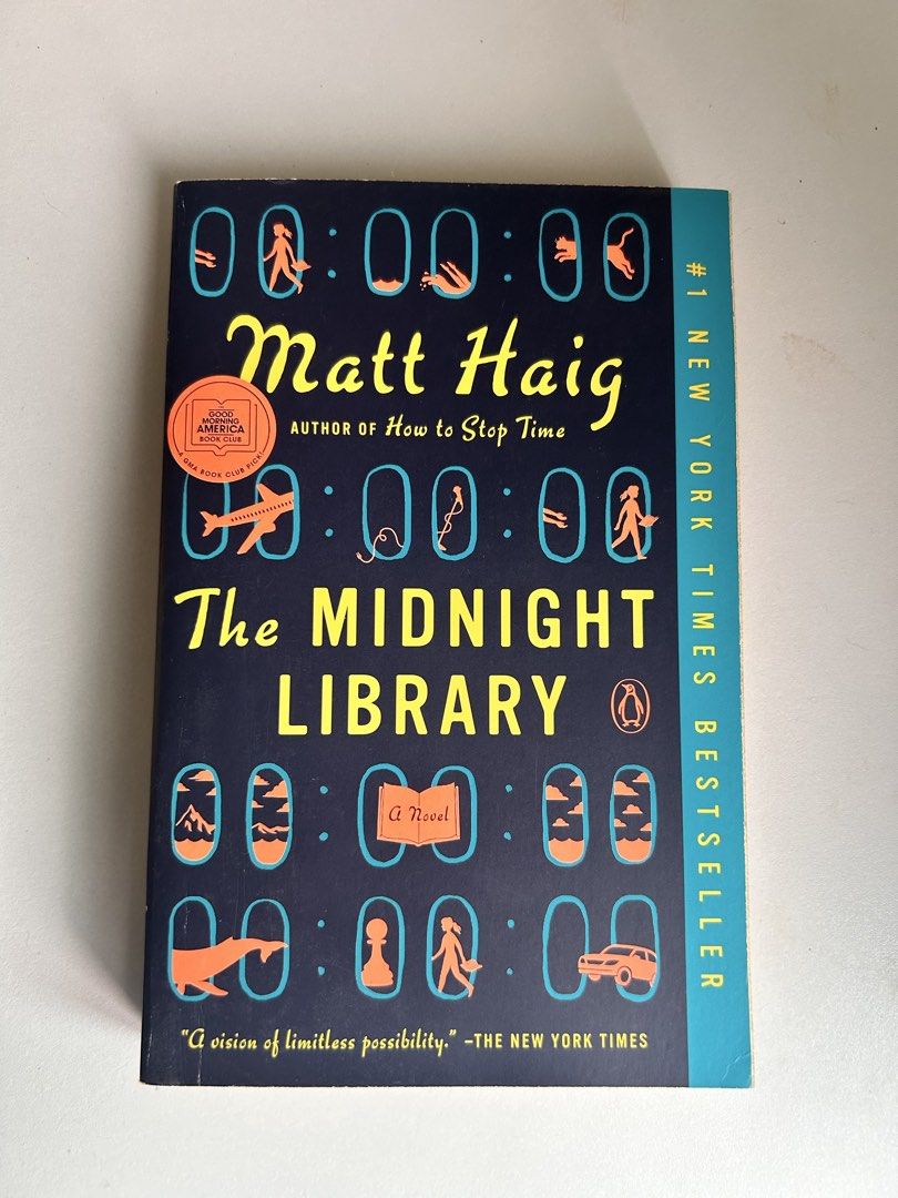 The Midnight Library by Matt Haig (Category: Storybooks) located in General Mariano Alvarez. Submitted by mochiii_72 (Listing ID 1465680000, Image 1). Description: - Title: The Midnight Library by Matt Haig - Status: #1 New York Times Bestseller (includes Good Morning America Book Club pick sticker) - Genre: Bestselling fiction exploring regret, choices, and parallel lives - Design: Dark blue cover with distinctive yellow and orange graphics - Co