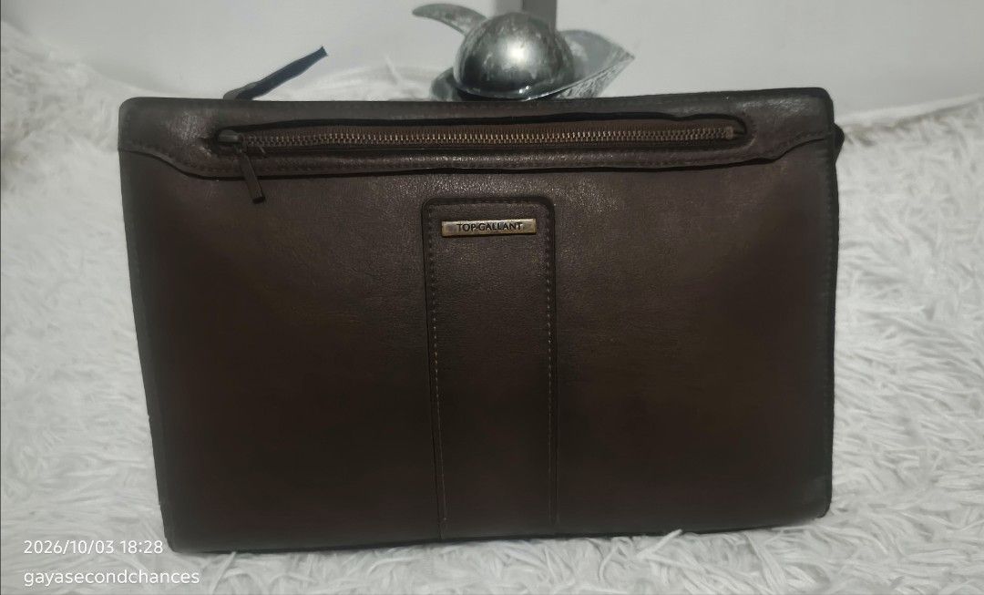 TOP GALLANT BROWN LEATHER CLUTCH BAG (Category: Belt bags, Clutches and Pouches) located in Kalibo. Submitted by secondchances.thriftsh8p (Listing ID 1465677557, Image 1). Description: - Brand: Top Gallant - Material: Brown leather - Closure: Secure zip-around design - Pocket: Handy front zippered pocket - Structure: Holds its shape with reinforced black side gussets - Details: Metal brand plaque and solid hardware.