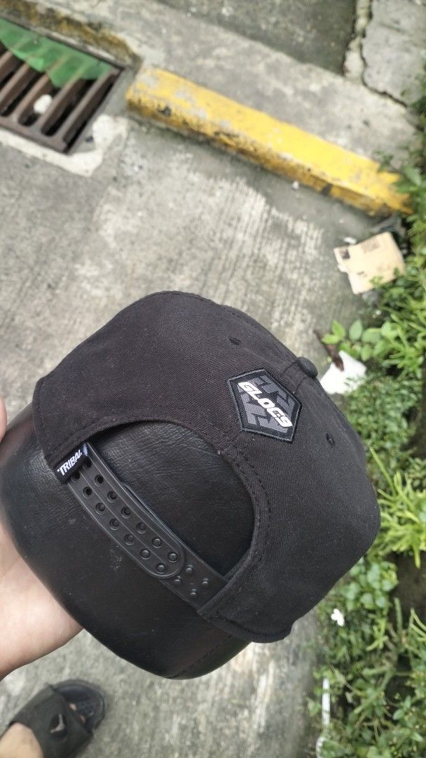 Tribal Gear x Gloc-9 Snapback Cap Black (Category: Caps & Hats) located in Manila. Submitted by chrisyoung01 (Listing ID 1465641104, Image 3). Description: - Style: Black snapback cap with standard fit and sturdy build - Front: Metallic silver Tribal logo - Side: 'Makata sa Pinas' embroidery with leaf design - Back: Gloc-9 patch and adjustable plastic strap .