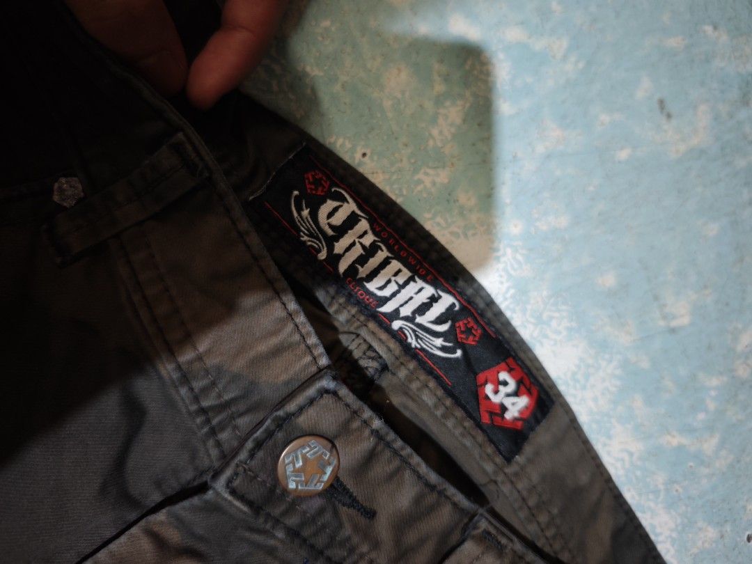 Tribal Worldwide Cargo Pants Size 34 Brown (Category: Jeans) located in Calauag. Submitted by cou1_h (Listing ID 1465639247, Image 3). Description: - Brand: Tribal Worldwide - Color: Brown - Size: 34 (marked on inner waistband tag) - Style: Classic street style cargo pants - Details: Heavy-duty fabric construction, multiple functional pockets, custom branded button, and unique embroidered tribal graphics on back pockets - Care: Machine wash cold 