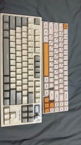 Two mechanical keyboards Langtu & rk71 (Category: Computer Keyboard) located in Manila. Submitted by gentlemountain.79a160 (Listing ID 1465696068, Image 1). Description: Bundle of 2 custom mechanical keyboards! Left board features cream/grey layout, rotary knob, digital screen, arrow cluster, and macro keys. Right board has a compact layout with orange spacebar and arrow accents. Both have tactile multi-color keycaps. Perfect as daily drivers or 