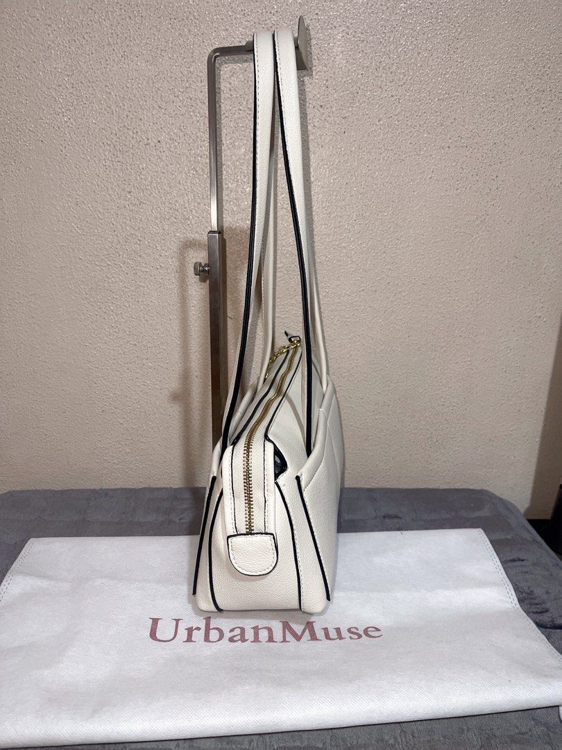 UrbanMuse White Shoulder Bag with Cherry Charm (Category: Shoulder Bags) located in Quezon City. Submitted by donnabelle7572 (Listing ID 1465668232, Image 3). Description: White leather-look shoulder bag from UrbanMuse. Gold zipper closure on top, double shoulder straps, structured rectangular shape. Outside pocket spans the front width, finished with gold-tone 'UM' lettering in the corner. Attached gold bow and red cherry keychain dangling from 