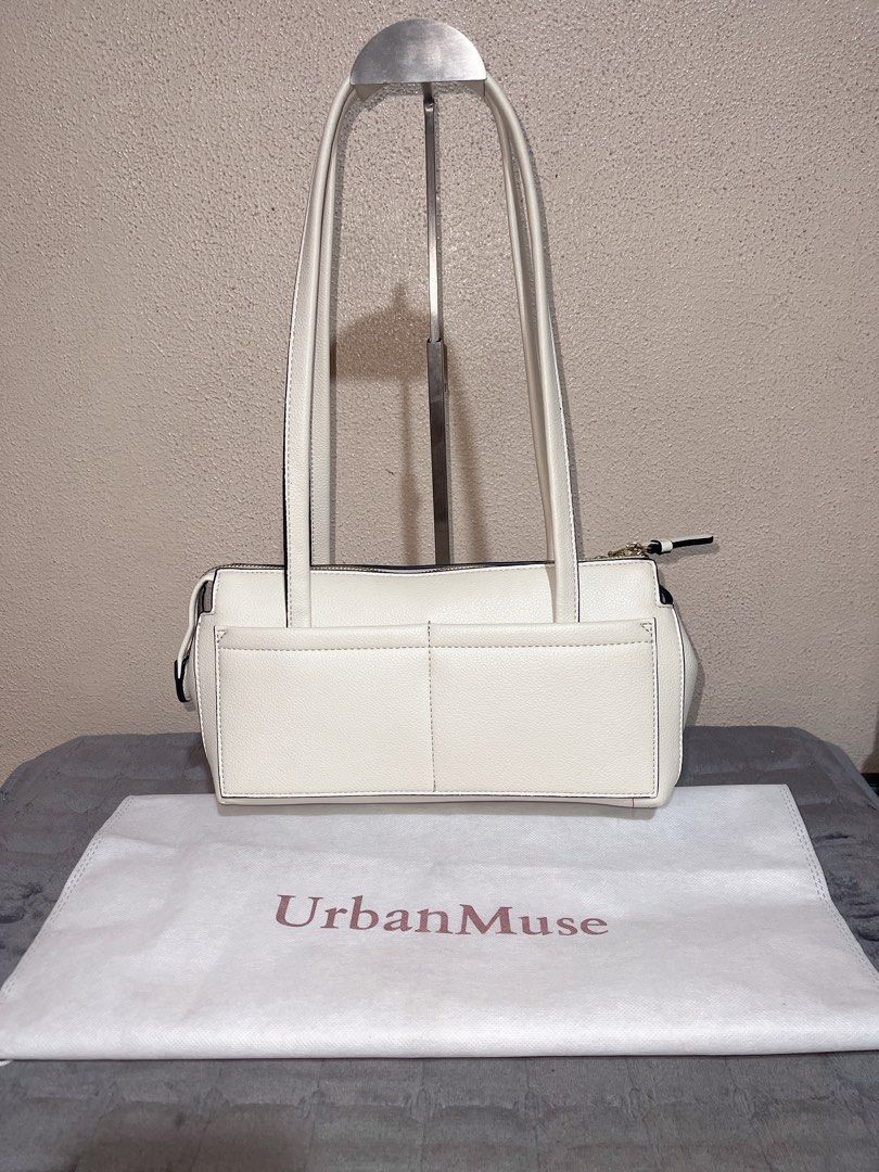 UrbanMuse White Shoulder Bag with Cherry Charm (Category: Shoulder Bags) located in Quezon City. Submitted by donnabelle7572 (Listing ID 1465668232, Image 2). Description: White leather-look shoulder bag from UrbanMuse. Gold zipper closure on top, double shoulder straps, structured rectangular shape. Outside pocket spans the front width, finished with gold-tone 'UM' lettering in the corner. Attached gold bow and red cherry keychain dangling from 