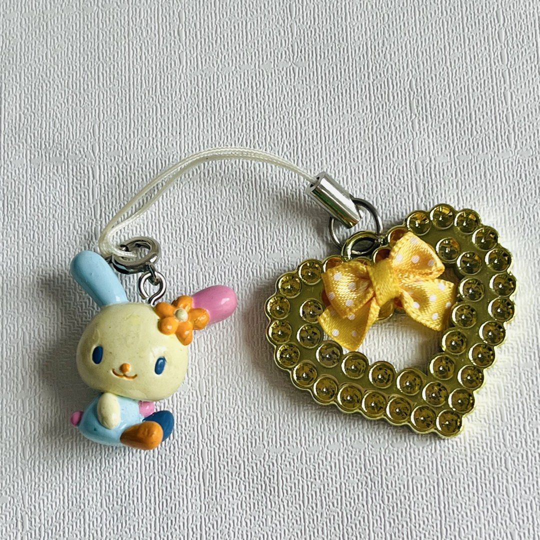 Usahana Sanrio 2001 2003 Phone Charm (Category: Charms) located in Cabuyao City. Submitted by nyannyancore (Listing ID 1465712845, Image 3). Description: - Authentic vintage Sanrio x Runa phone strap (©'01, '03) - Features an adorable bunny with mismatched ears and flower detail - Accented with a gold rhinestone heart charm and yellow polka dot ribbon - Includes white strap loop - Perfect rare collectible for Sanrio lovers and Y2K aesthetic fans.