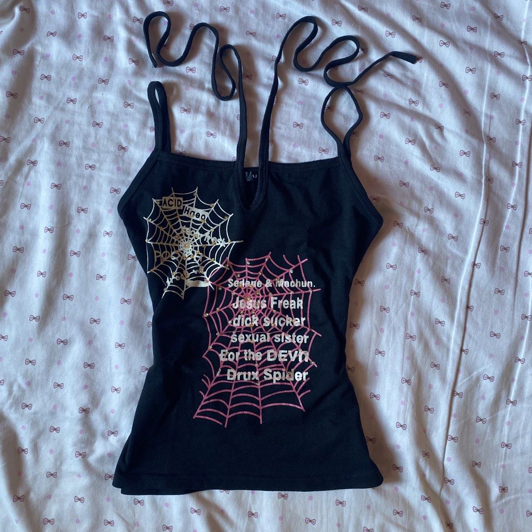 UZ Black Graphic Cami Top with Spiderweb Print (Category: Sleeveless) located in Abulug. Submitted by dear_darlingdoll (Listing ID 1465718488, Image 1). Description: - Brand: UZ - Color: Black with white and pink graphics - Material: Comfortable cotton - Design: Double straps with tie details - Accents: Spiderweb graphic, text, and rhinestone embellishments - Style: Alternative streetwear, y2k aesthetic - Condition: Excellent / Like new - Mode of
