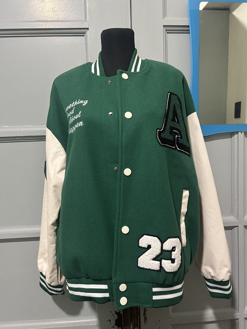Varsity Jacket Letter A (Category: Coats, Jackets and Outerwear) located in Manila. Submitted by yuShin09 (Listing ID 1465631349, Image 2). Description: - Color: Green and white - Closure: Snap button front fits Medium to Large as its a bit oversize - Sleeves are synthetic leather - Design: Embroidered 'A' and '23', right chest text "Something Good Is About To Happen", and a heart patch on the right sleeve.
