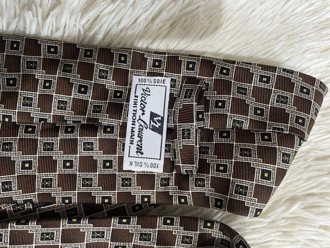 Victor Laurent 100% Silk Brown Geometric Tie (Category: Ties) located in Bulacan. Submitted by rich2545 (Listing ID 1465581293, Image 3). Description: - Brand: Victor Laurent - Material: 100% Soie Silk (Handmade finish) - Design: Brown with geometric gold and white square details - Width: Standard - Condition/Details: Clean lining on the back - Ideal for: Work, meetings, or formal events.