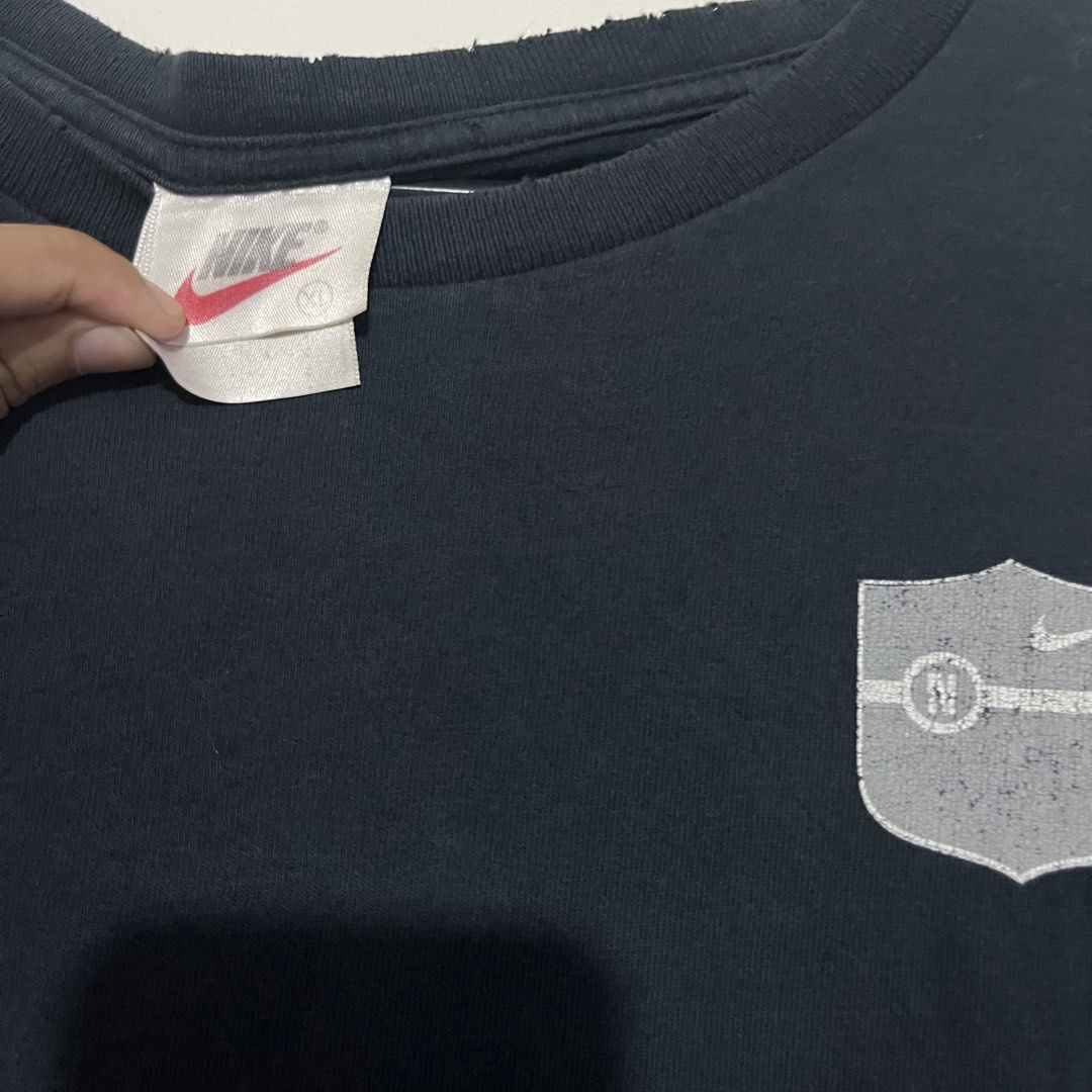 Vintage Nike Athletics Courage Commitment Challenge T-Shirt (Category: Tshirts & Polo Shirts ) located in Caloocan City. Submitted by thrivo.co (Listing ID 1465633518, Image 3). Description: - Brand: Nike - Style: Vintage Nike Athletics t-shirt - Color: Black - Size: Medium (Classic red Nike swoosh tag) - Front: Distressed shield graphic - Back: Bold 'NIKE ATHLETICS COURAGE COMMITMENT CHALLENGE' lettering with swoosh - Condition: Soft fabric with
