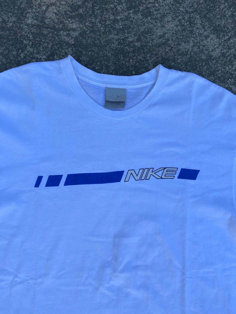 Vintage Nike White Blue Graphic Tee (Category: Tshirts & Polo Shirts ) located in Calabanga. Submitted by 4405.curator (Listing ID 1465594463, Image 3). Description: White Nike t-shirt with a blue graphic stripe and bold logo across the chest. Crew neckline, short sleeves. Size XL, made in Mexico. Classic retro look from the silver tag era. Got a few tiny faint marks near the front graphic stripe, check the close-up photo. Fabric feels well-worn 