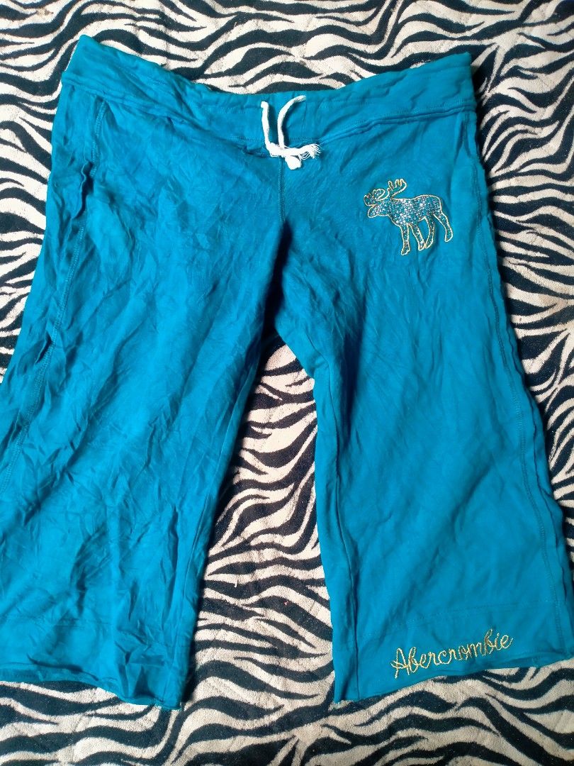 vintage turquoise Abercrombie Capri (Category: Other Bottoms) located in Maco. Submitted by nothingabove300shop (Listing ID 1465614491, Image 2). Description: AI Overview The image shows a pair of vintage turquoise/blue Y2K Abercrombie & Fitch sweatpant capris or shorts featuring a signature moose logo with glitter details and an "Abercrombie" script logo near the hem. size-L ( adjustable).