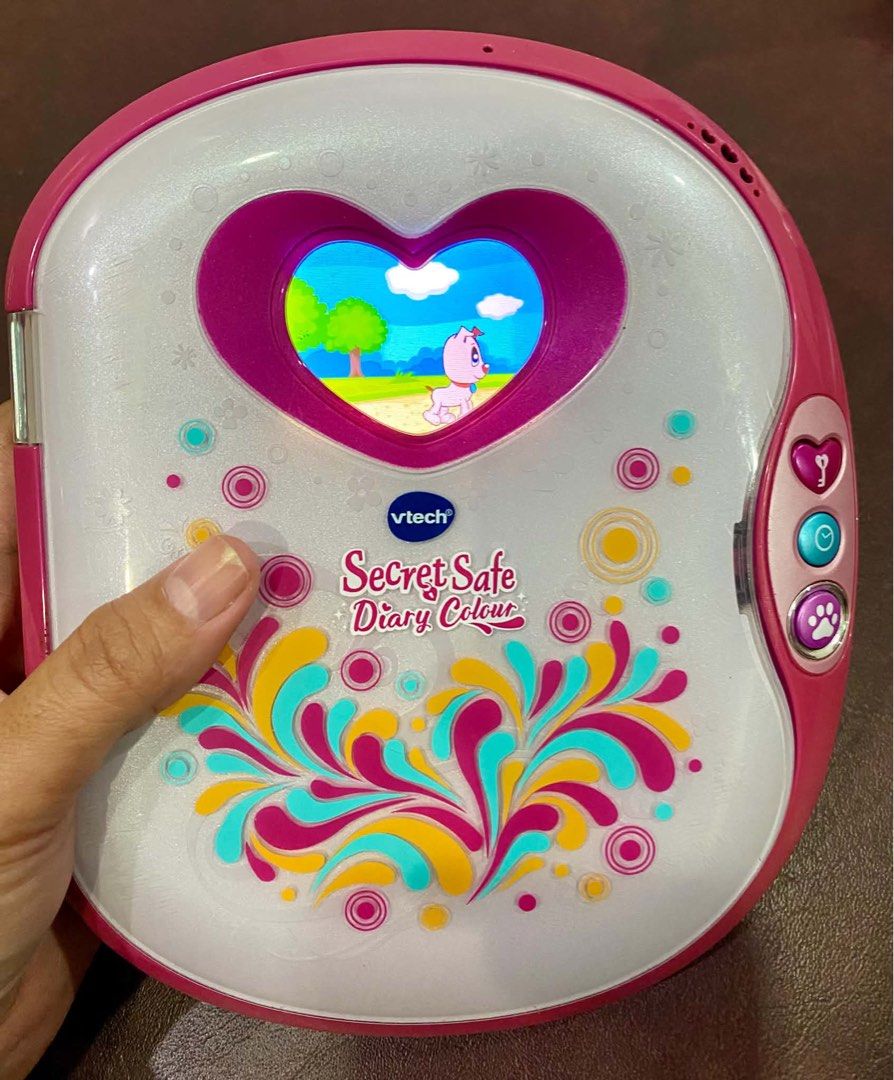 VTech Secret Safe Diary Colour (Category: Educational & Learning Toys) located in Cagayan de Oro. Submitted by sethmarko27 (Listing ID 1465580841, Image 1). Description: - Pink and white VTech Secret Safe Diary Colour for kids - Adorable heart-shaped screen with fun animations and digital pet features - Side buttons include a lock icon, clock, and paw print - Beautiful white body covered in colorful floral and swirl graphics - Fully tested and wo