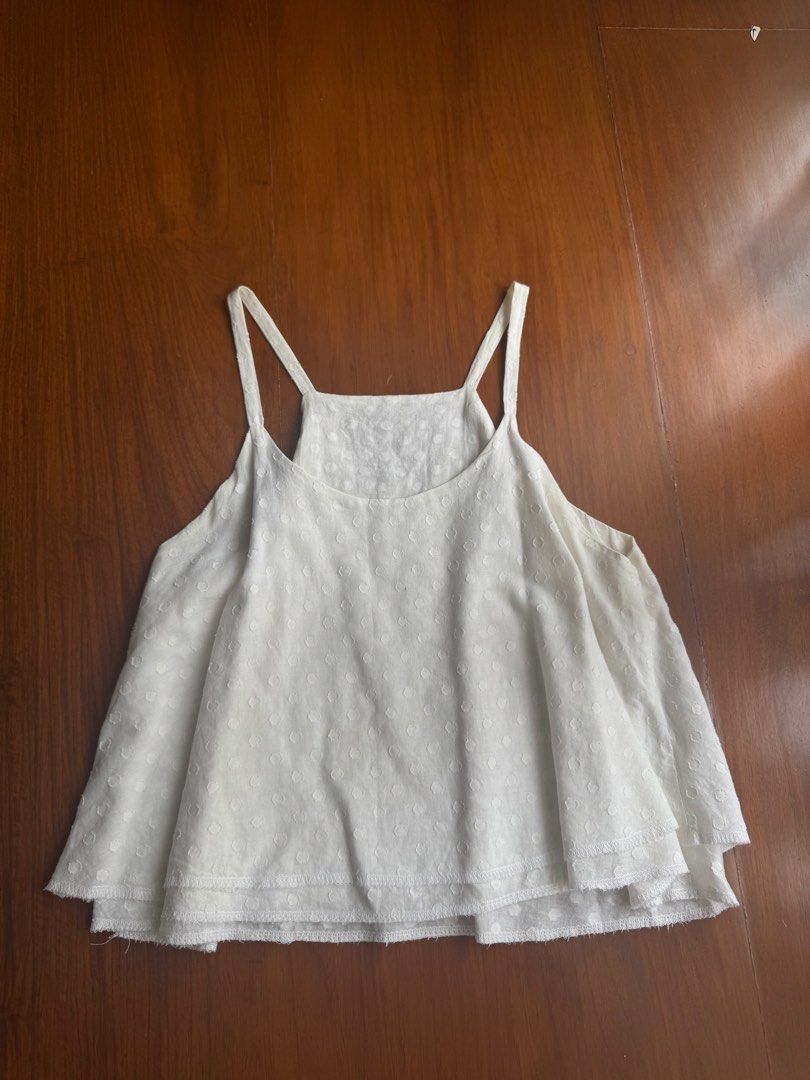 White Polka Dot Halter Tank Top (Category: Sleeveless) located in Pasig City. Submitted by kutleyn (Listing ID 1465653605, Image 1). Description: - Color: White - Pattern: Textured Swiss dot - Design: Square neckline with thin spaghetti straps - Fit: Flowy, loose fit with a stylish double-layered hem - Fabric: Lightweight and breathable for warm weather - Versatility: Easy to pair with shorts, jeans, or skirts for casual outings.