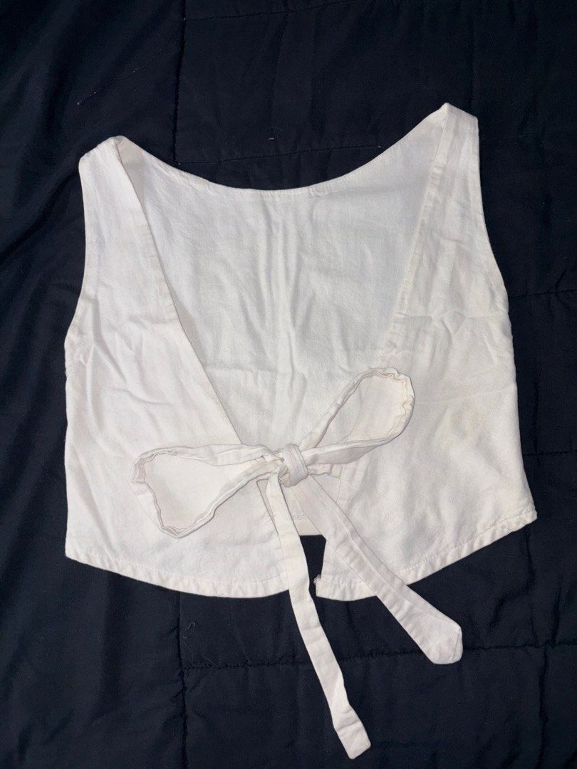 White sleeveless crop top with back tie (Category: Sleeveless) located in Quezon City. Submitted by katedeclutter (Listing ID 1465594067, Image 2). Description: - Color: White - Style: Sleeveless crop top with scoop neckline - Design: Open back with lower fabric tie closure - Fit: Short length, straight hem - Material: Lightweight woven fabric - Versatility: Neutral shade that pairs easily with any bottoms, perfect for casual or warm-weather outf