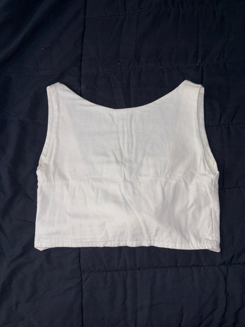 White sleeveless crop top with back tie (Category: Sleeveless) located in Quezon City. Submitted by katedeclutter (Listing ID 1465594067, Image 1). Description: - Color: White - Style: Sleeveless crop top with scoop neckline - Design: Open back with lower fabric tie closure - Fit: Short length, straight hem - Material: Lightweight woven fabric - Versatility: Neutral shade that pairs easily with any bottoms, perfect for casual or warm-weather outf