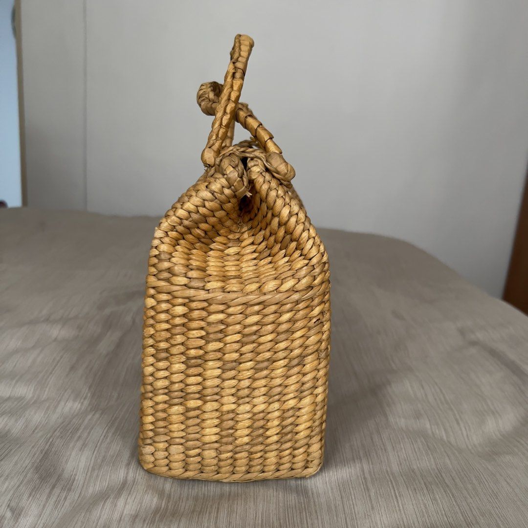 Woven Straw Handbag Structured Top Handle Basket Bag (Category: Beach Bags) located in Pasig City. Submitted by jenscloset86 (Listing ID 1465703700, Image 2). Description: • Natural woven straw handbag with a rigid structured shape and flat rectangular base. • Normal wear in one handle due to usage. • Double braided top handles with decorative knot accents and an open top. • Lightweight, easy to carry. • Perfect for summer! Measurement (in inches