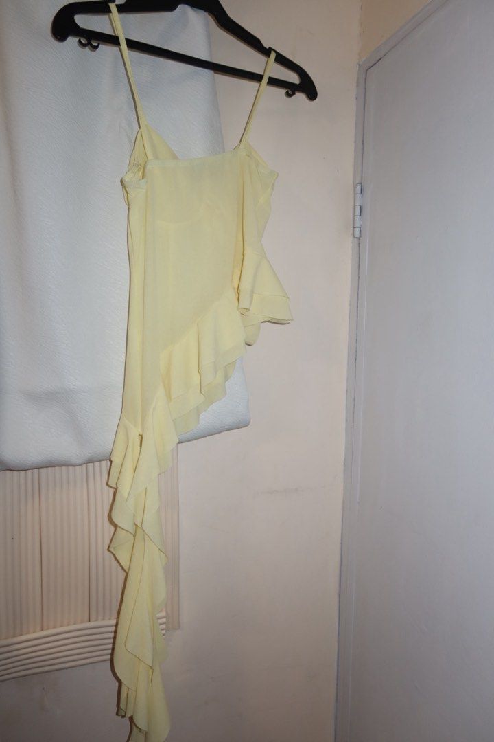 Yellow Asymmetric Ruffle Camisole Top (Category: Sleeveless) located in Cavite. Submitted by mcjkim (Listing ID 1465703156, Image 2). Description: - Brand: Klalien - Color: Vibrant yellow - Style: Spaghetti strap camisole with an asymmetric cascading ruffle hem - Detail: Charming fabric rose accent on the front bodice - Material: Lightweight and breezy, ideal for summer outings or night walks - Condition: Worn only once in Hoi An, Vietnam.