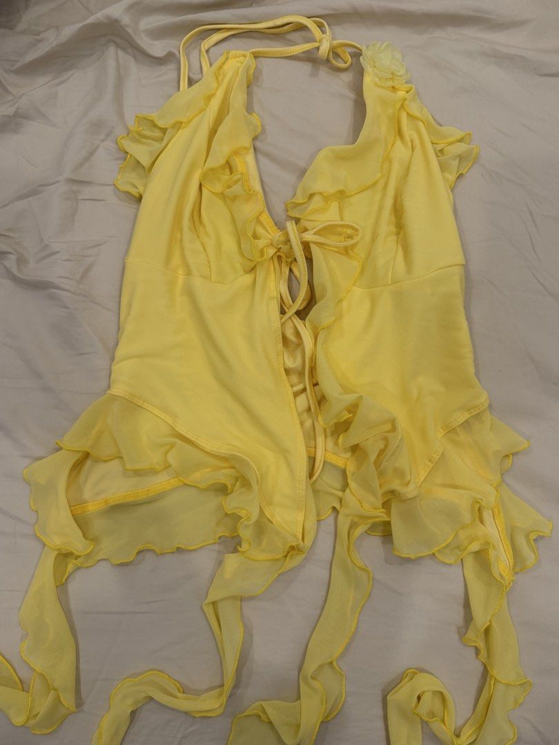 Yellow Halter Ruffle Tie Front Mesh Top Size S (Category: Sleeveless) located in Calamba. Submitted by miss.ksnap (Listing ID 1465646530, Image 1). Description: - Color: Bright yellow - Material: Sheer, lightweight mesh - Size: Small (S) - Design: Halter neck with adjustable front tie straps - Details: Playful ruffles along the edges and a cute floral applique on the strap - Origin: Made in China.