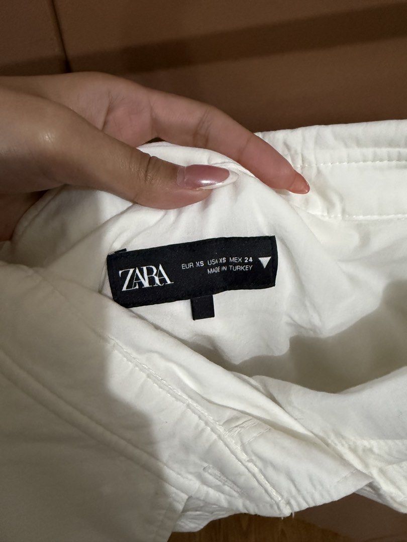 Zara Off-Shoulder Asymmetrical Button Top (Category: Blouses) located in Quezon City. Submitted by declutterbycy (Listing ID 1465758768, Image 2). Description: - Brand: Zara - Size: XS - Color: White - Material: Structured cotton-blend with ruching - Details: Off-shoulder, asymmetrical front button placket, folded collar - Origin: Made in Turkey - Condition: Clean, excellent, and ready to wear - Styling: Versatile piece that pairs easily with den