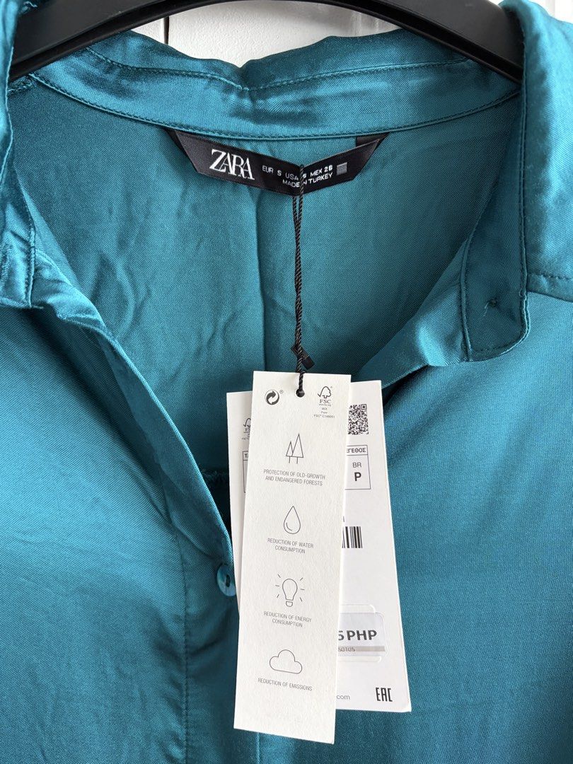 Zara Teal Satin Oversized Button-Up Shirt Size S (Category: Blouses) located in Bacolod City. Submitted by francine_favss (Listing ID 1465597363, Image 2). Description: - Brand: Zara - Size: Small (oversized, can fit to plus size) - Color: Teal - Material: Flowy, lightweight satin with a subtle glossy finish - Design: Pointed collar, front button closure, long sleeves with button cuffs, high-low curved hemline - Condition: Brand new with original