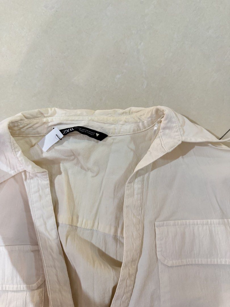 ZARA White Crop Shirt Size (Category: Shirts) located in Quezon City. Submitted by sweetlyluxe (Listing ID 1465623158, Image 3). Description: - Brand: Zara - Size: EUR XS / USA XS / MEX 24 - Color: White - Material: Lightweight textured fabric (Made in Turkey) - Details: Short cuffed sleeves, classic collar, dual chest pockets, and front tie-knot hem - Styling: Great to pair with high-waisted denim or skirts - Condition: yellowish on some parts, 