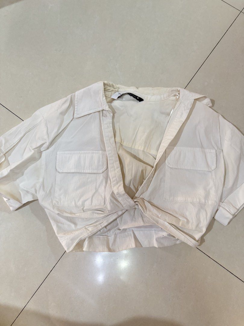 ZARA White Crop Shirt Size (Category: Shirts) located in Quezon City. Submitted by sweetlyluxe (Listing ID 1465623158, Image 1). Description: - Brand: Zara - Size: EUR XS / USA XS / MEX 24 - Color: White - Material: Lightweight textured fabric (Made in Turkey) - Details: Short cuffed sleeves, classic collar, dual chest pockets, and front tie-knot hem - Styling: Great to pair with high-waisted denim or skirts - Condition: yellowish on some parts, 