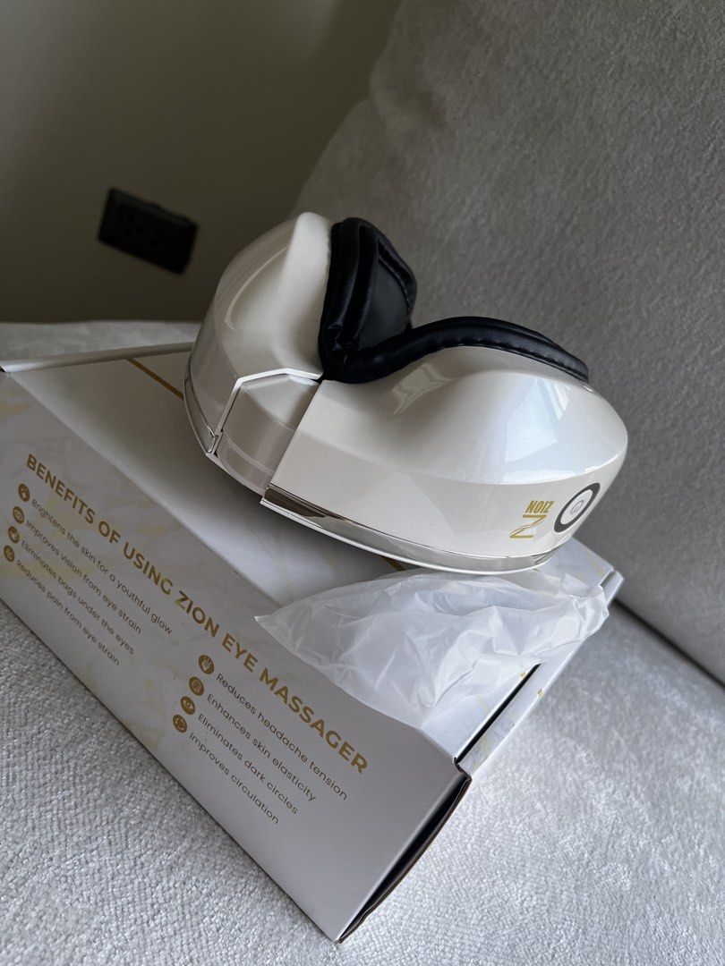 Zion Eye Massager (Category: Massage Devices) located in Quezon City. Submitted by burugandini (Listing ID 1465680383, Image 2). Description: - Brand: Zion Eye Massager - Color: White with stylish black padding - Condition: Unused inside the original retail box with protective packaging - Key Benefits: Reduces eye strain, headaches, dark circles, and under-eye bags - Extra Perks: Improves blood circulation and skin elasticity.