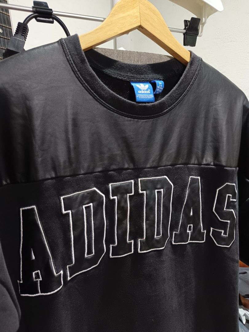 Adidas Black Graphic T-Shirt (Category: Tshirts & Polo Shirts ) located in Santiago. Submitted by PjThrift (Listing ID 1471254819, Image 2). Description: - Brand: Adidas Originals - Color: Black with oversized white chest logo - Size: 34 (165/80A) - Material: 70% cotton, 30% polyester shell; 100% polyester faux leather upper panel and sleeves - Design: Crew neck, small logo tag on left sleeve hem, made in Indonesia - Style: Casual streetwear, com