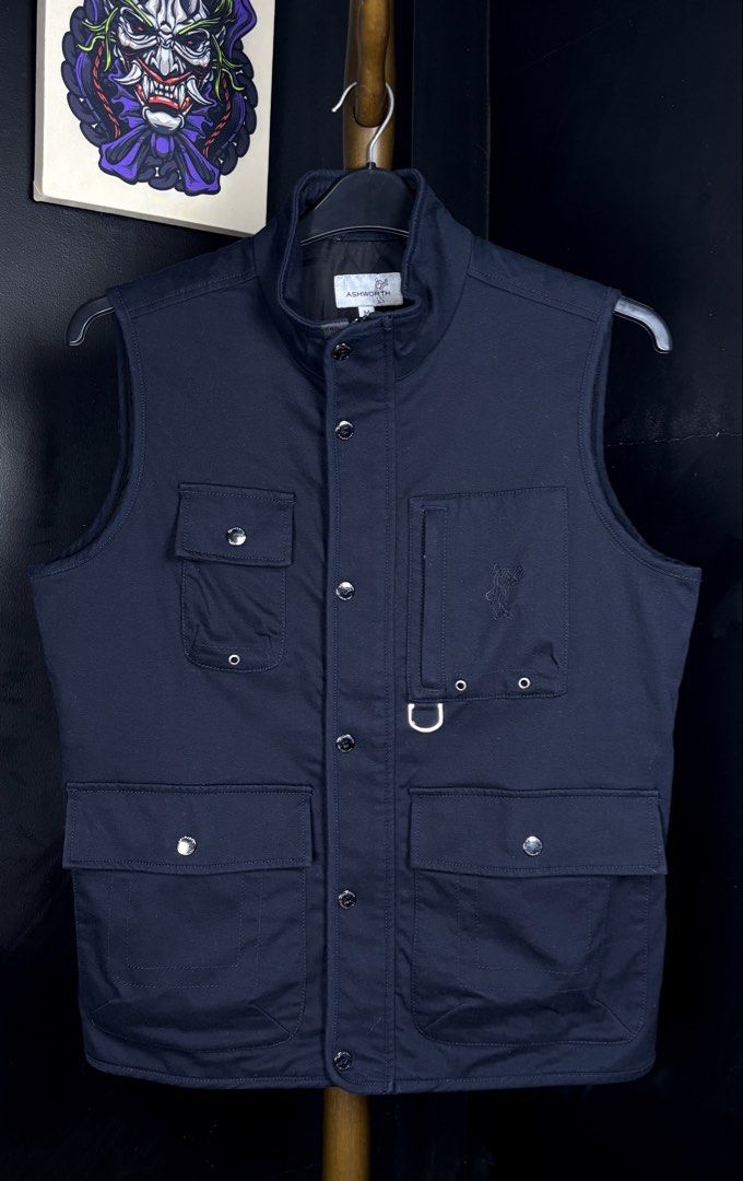 Ashworth Full-Zip With Buttons Vest (Category: Vests) located in Bacoor. Submitted by calvinmanzano13 (Listing ID 1471221806, Image 1). Description: - L = 25.5” | W = 21” - Color: Navy Blue - Warm quilted inner lining - Multiple front flap pockets with metal snap buttons - Extra chest zipper compartment and D-ring detail - Full zip closure with snap button placket - Stand-up collar - Clean fabric and hardware, great for layering Notes: 🔥 Hand wa