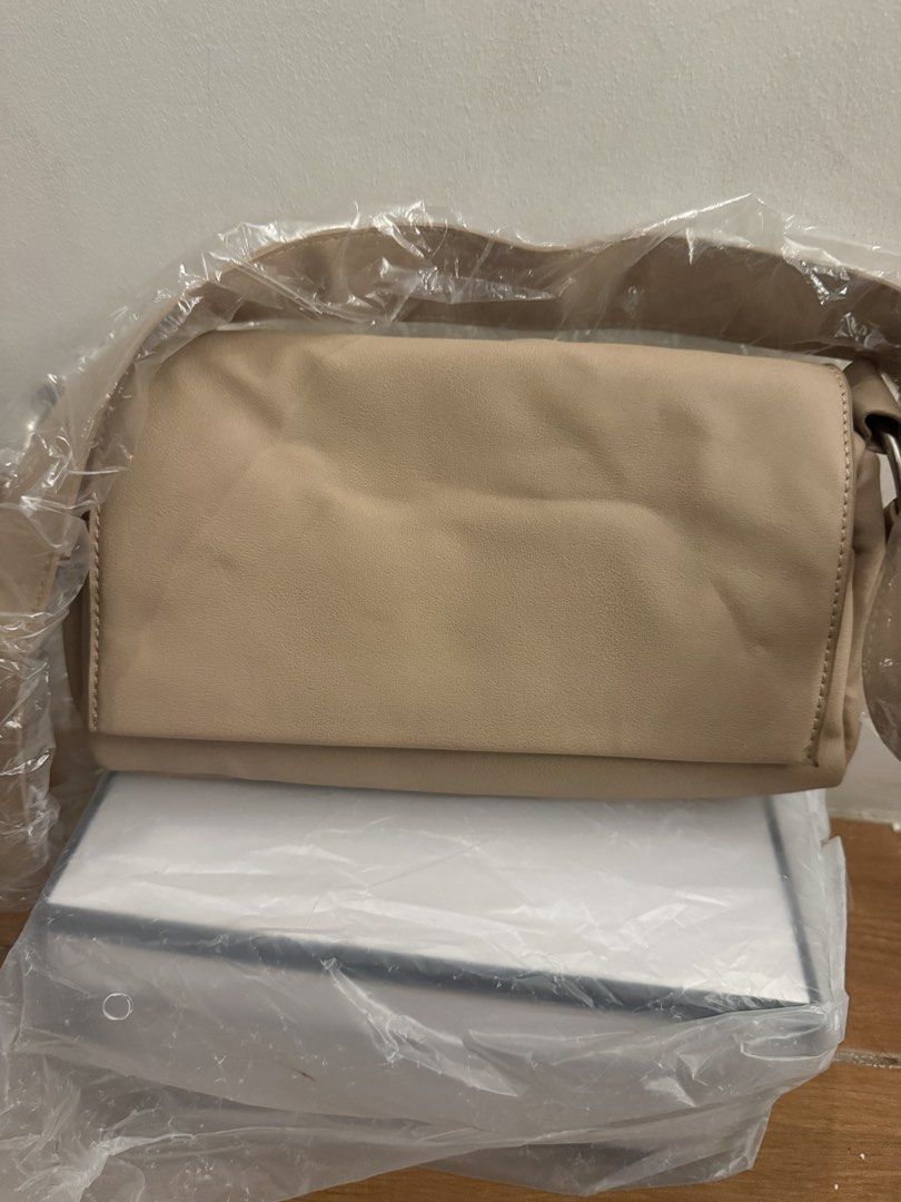 Beige Shoulder Bag Flap Closure (Category: Shoulder Bags) located in Bulacan. Submitted by emjay_17 (Listing ID 1471218356, Image 1). Description: - Color: Elegant beige - Style: Flap top shoulder bag - Material: Soft and smooth texture - Interior: Clean nude lining with zippered compartments - Size: Approx. 25cm (L) x 15cm (H) - Condition: Brand new, still wrapped in plastic protection.