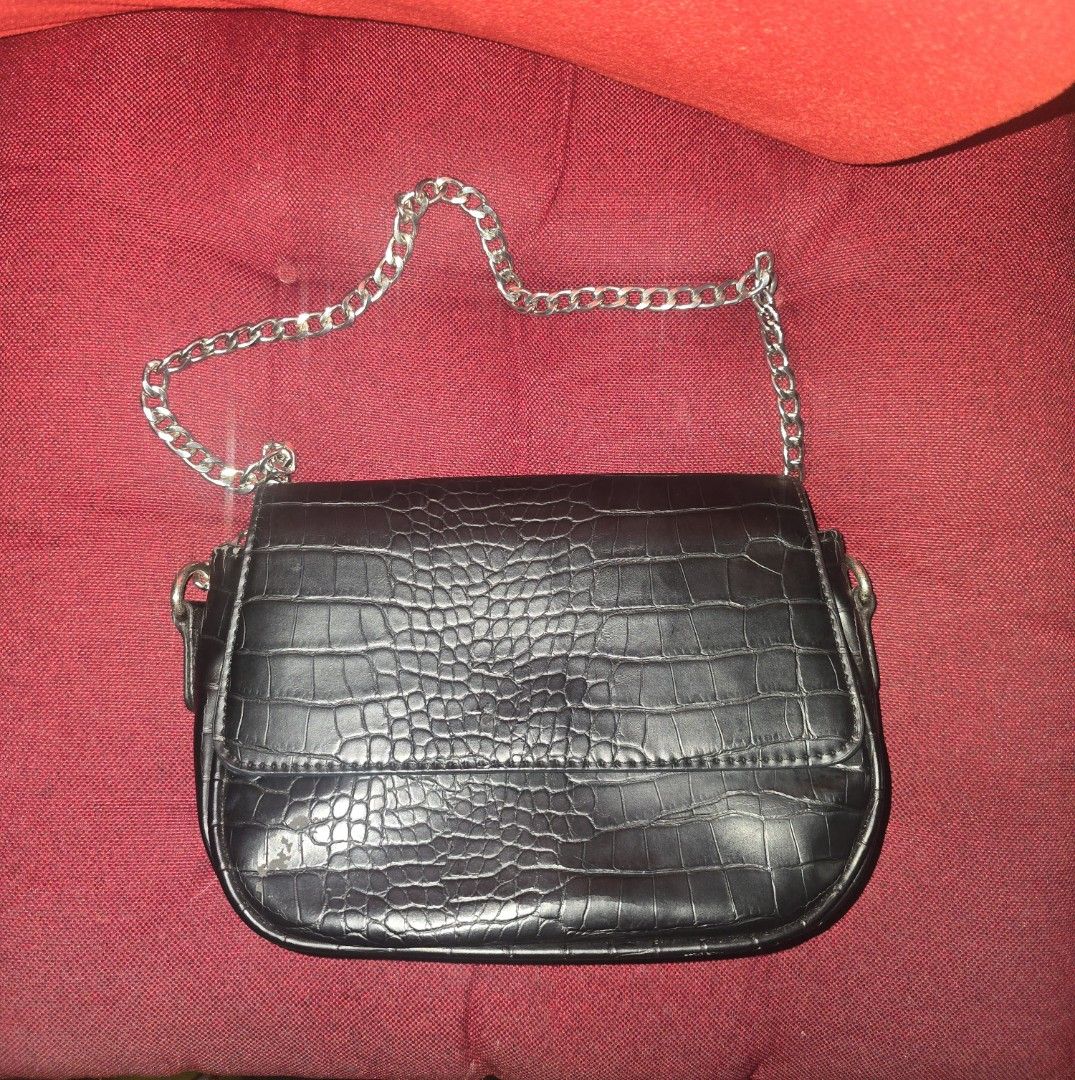 Bershka Black Croc Embossed Shoulder Bag with Silver Chain (Category: Shoulder Bags) located in Paranaque City. Submitted by ccc_finds (Listing ID 1471269355, Image 1). Description: - Color & Texture: Black with an all-over croc-embossed pattern - Strap: Sleek silver chain attached to both sides - Closure: Flap style with rounded bottom edges - Capacity: Compact size, perfect for small daily essentials - Condition: Good, with a minor scuff visibl