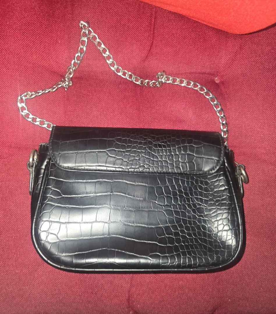 Bershka Black Croc Embossed Shoulder Bag with Silver Chain (Category: Shoulder Bags) located in Paranaque City. Submitted by ccc_finds (Listing ID 1471269355, Image 2). Description: - Color & Texture: Black with an all-over croc-embossed pattern - Strap: Sleek silver chain attached to both sides - Closure: Flap style with rounded bottom edges - Capacity: Compact size, perfect for small daily essentials - Condition: Good, with a minor scuff visibl