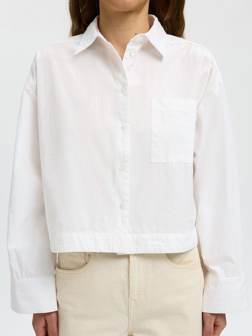 Bershka White Cropped Button-Up Shirt (Category: Shirts) located in San Juan City. Submitted by declutterwithxz (Listing ID 1471178054, Image 1). Description: - Brand: Bershka - Style: Cropped button-down shirt with a relaxed silhouette and dropped shoulders - Details: Pointed collar, single chest pocket, and long sleeves with wide cuffs - Size: XS - Origin: Made in India - Versatility: Essential basic piece, ideal for layering or styling solo wi