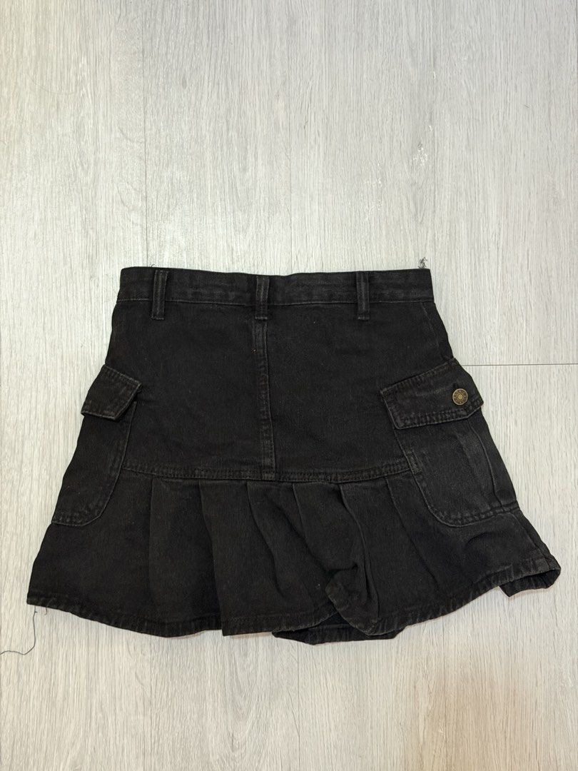 Black Denim Cargo Pleated Skirt (Category: Skirts) located in Manila. Submitted by prelovedbychellyy (Listing ID 1471175371, Image 2). Description: - Style: Y2K street style, flared hem - Design: Pleated with functional utility pockets on both sides - Details: Mid-rise waistband, belt loops, front button fastening - Material: Comfortable cotton denim - Condition: Excellent, no flaws or stains, clean inside and out.