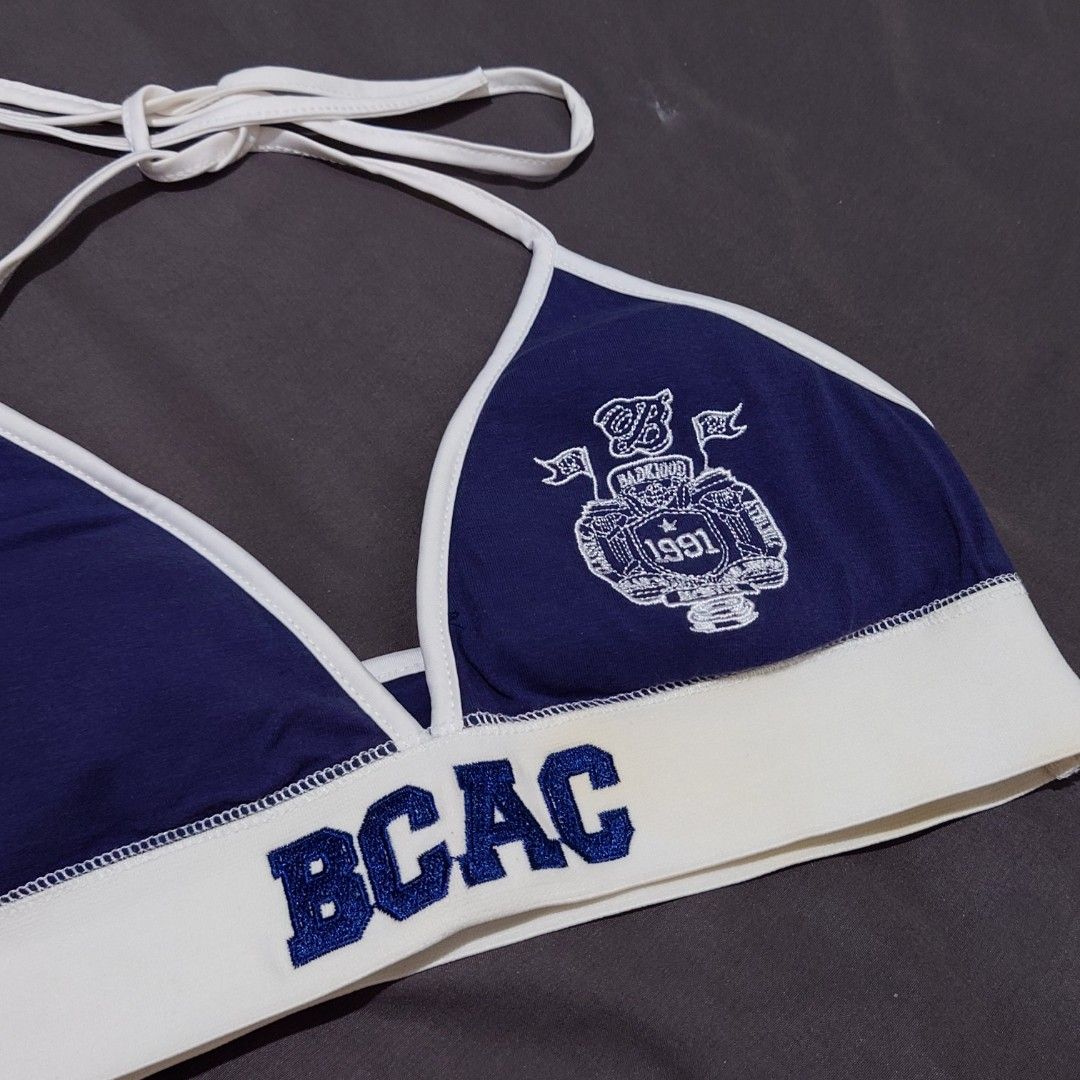 Blue and White Halter Top with BCAC Print (Category: Sleeveless) located in Diffun. Submitted by declutteredbyJill (Listing ID 1471233890, Image 3). Description: - Navy blue and white halter top with adjustable neck ties - Thick elastic underbust band featuring bold 'BCAC' lettering - Detailed white collegiate crest emblem with '1991' on the right cup - Stylish white trim framing the triangle cups - Made from a comfortable, soft cotton-blend fabr
