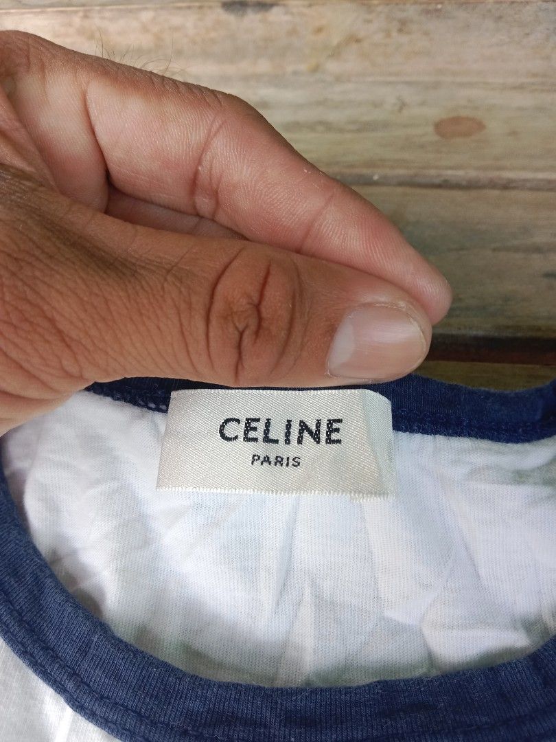 Celine Paris White Ringer T-Shirt Size M (Category: Shirts) located in Manila. Submitted by nadyrl (Listing ID 1471243140, Image 3). Description: - Brand: Celine Paris - Design: White ringer tee with blue trim on collar and sleeves - Graphic: Large black Celine logo and Triomphe graphic on chest - Material: 100% cotton, Made in Italy - Size: Medium (M) - Fit: Regular fit, classic casual everyday wear.
