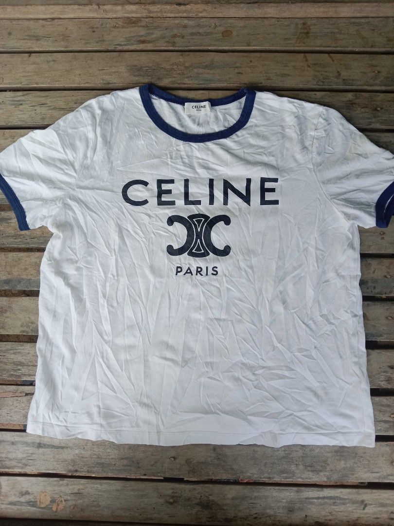 Celine Paris White Ringer T-Shirt Size M (Category: Shirts) located in Manila. Submitted by nadyrl (Listing ID 1471243140, Image 1). Description: - Brand: Celine Paris - Design: White ringer tee with blue trim on collar and sleeves - Graphic: Large black Celine logo and Triomphe graphic on chest - Material: 100% cotton, Made in Italy - Size: Medium (M) - Fit: Regular fit, classic casual everyday wear.
